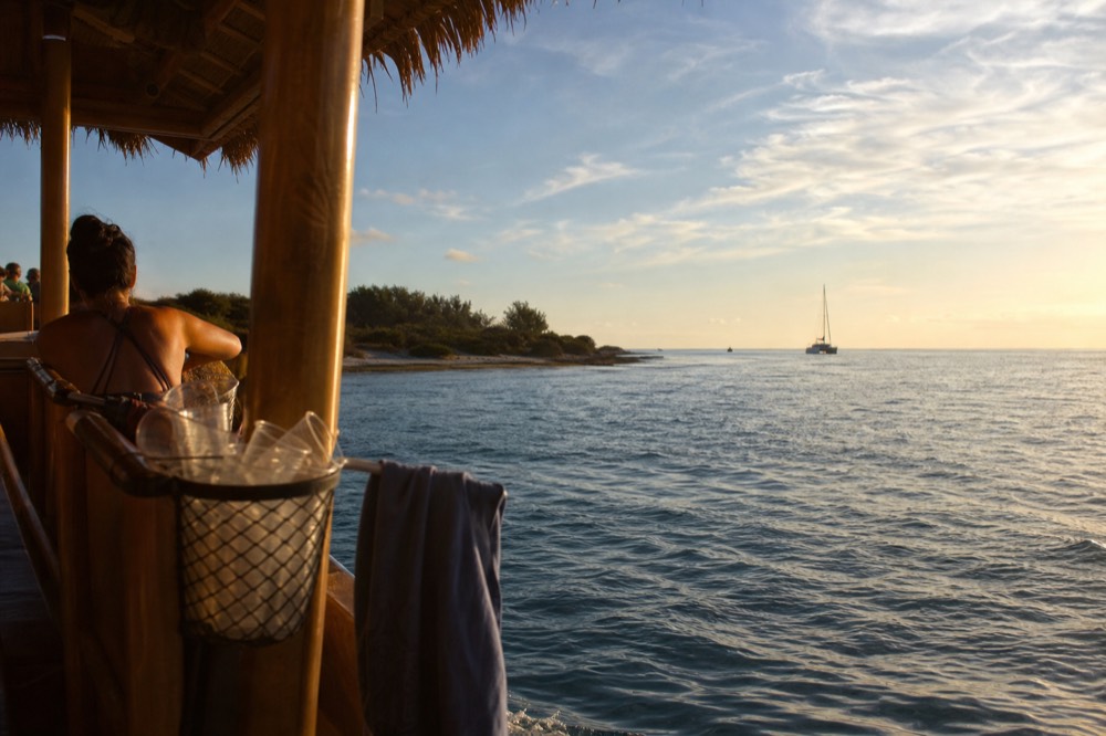 A tiki-style boat cruising on open water near Key West at golden hour, no text, no logos, no people.