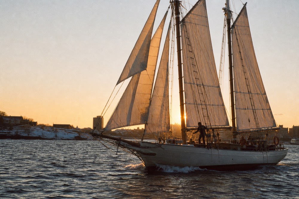 Schooner under full sail at sunset, no text, no logos, no people