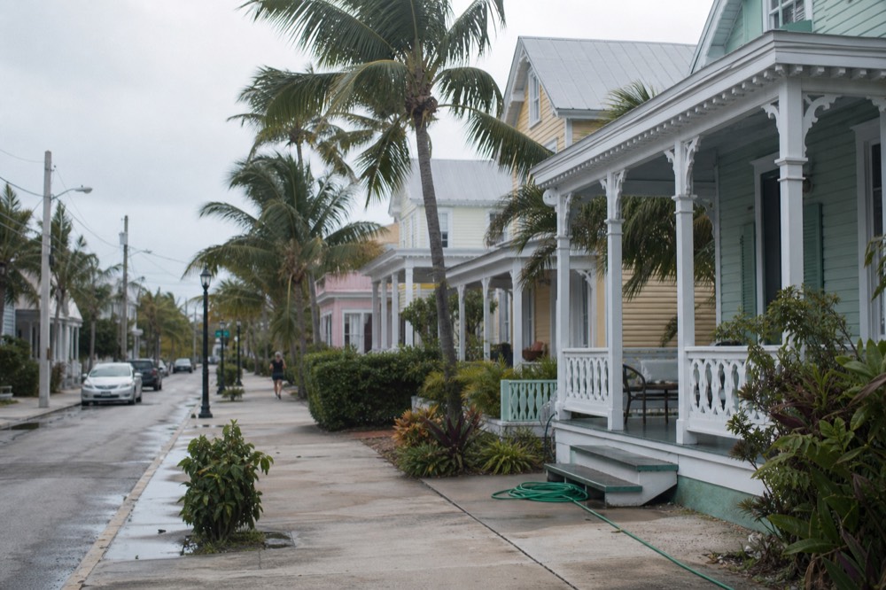Palm-lined flat street with pastel conch-style houses in Key West, no text, no logos, no people