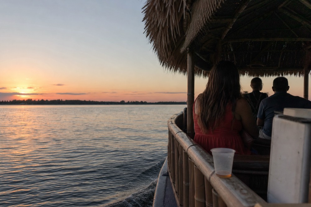 A small tiki-style boat cruising on flat water at sunset near Key West, no text, no logos, no people