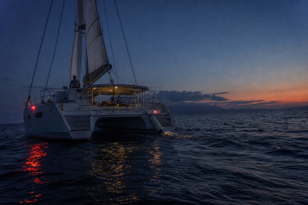 A catamaran under sail on open water near Key West at dusk, no text, no logos, no people.